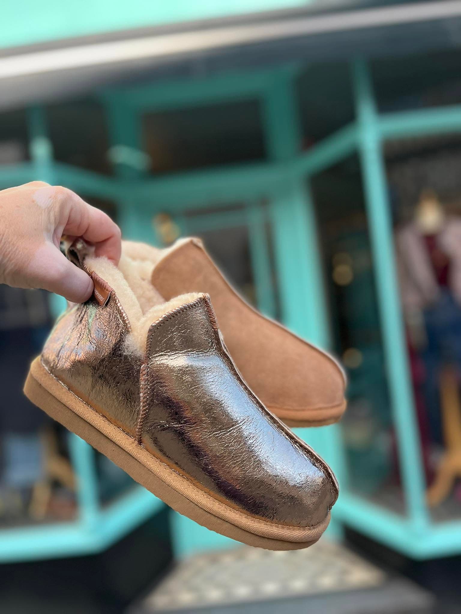 A shoe held outside Ella Cru's turquoise shopfront